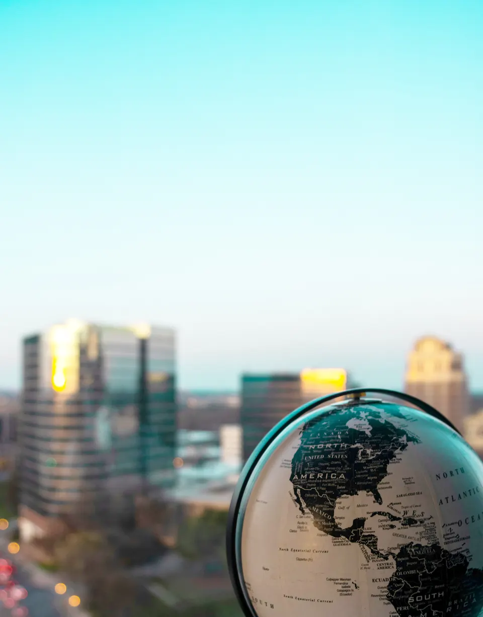 A globe on a desk with a city skyline behind it